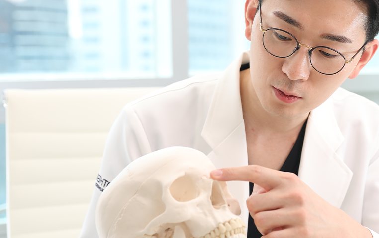 전문의 전담 관리제 — 두개골 모형을 짚으며 설명하는 의료진